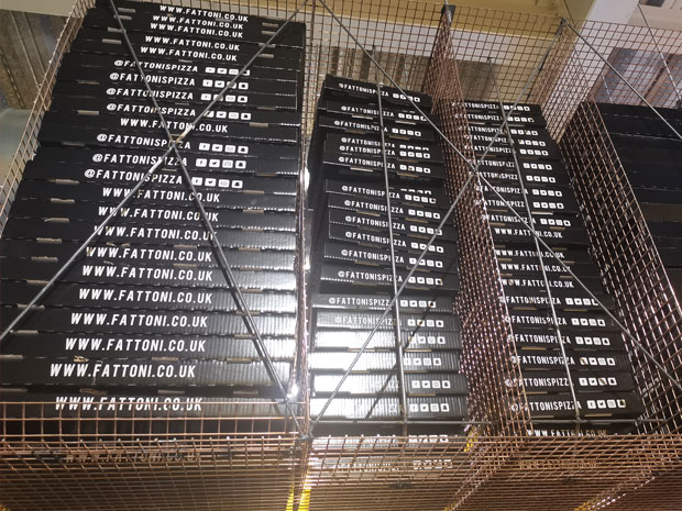 Industrial style shelving holds pizza boxes, ready for delivery.