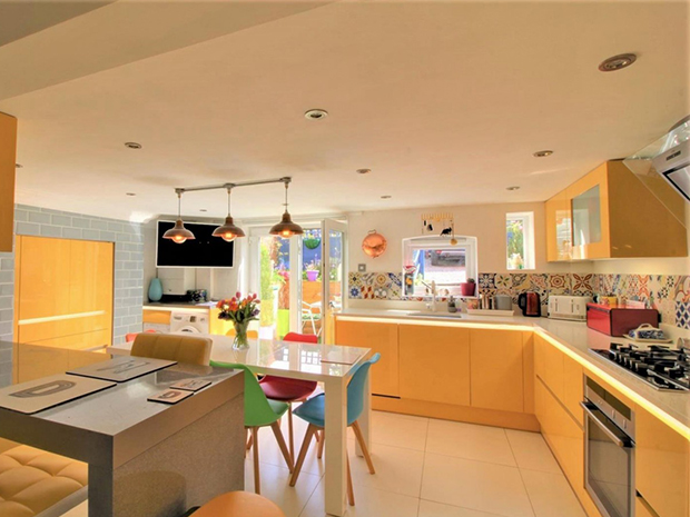 The bright, modern kitchen has a breakfast bar, Neff appliances and French doors out to a sunny courtyard.