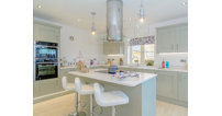 The bright kitchen dining area has a feature island, integrated appliances and silestone worktops.