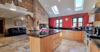 Meanwhile, the kitchen, living and dining area feature stylish appliances including an Esse wood-burning stove, as well as room for a family dining table and sitting room.